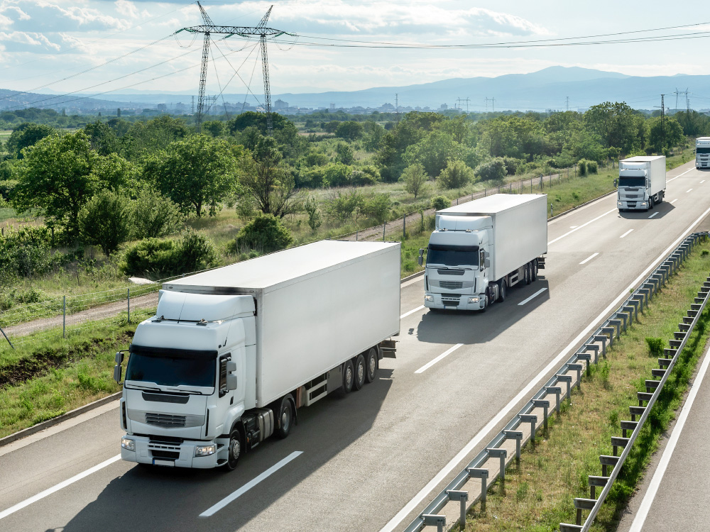 Large trucks driving on a highway, illustrating ST-OPV integration into mobility and vehicle applications